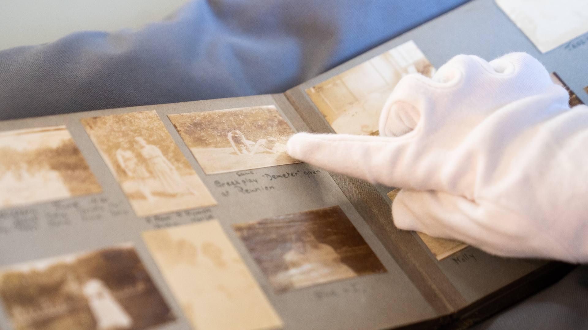 A gloved hard touches a very old book.
