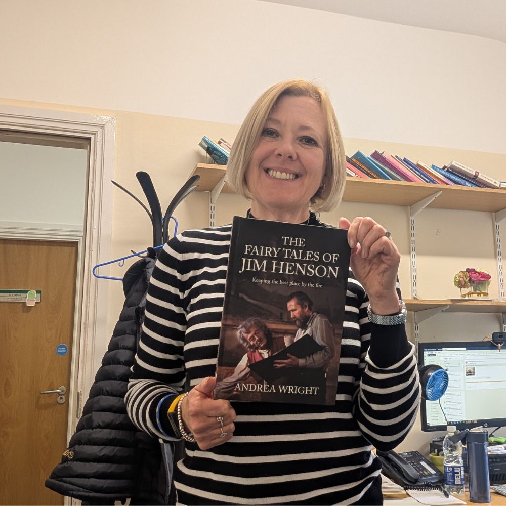 Andrea Wright holding a book and smilling at the camera 