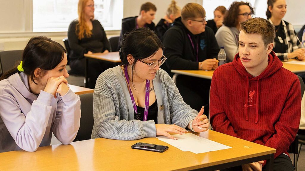 Students working together in a classroom setting with materials on desk