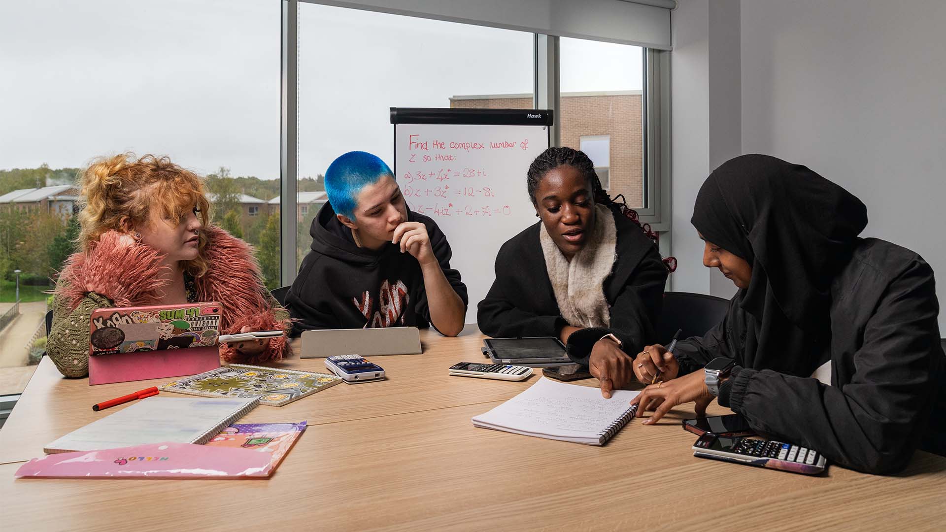 Mathematics students sat around a table with calculators and pen and paper