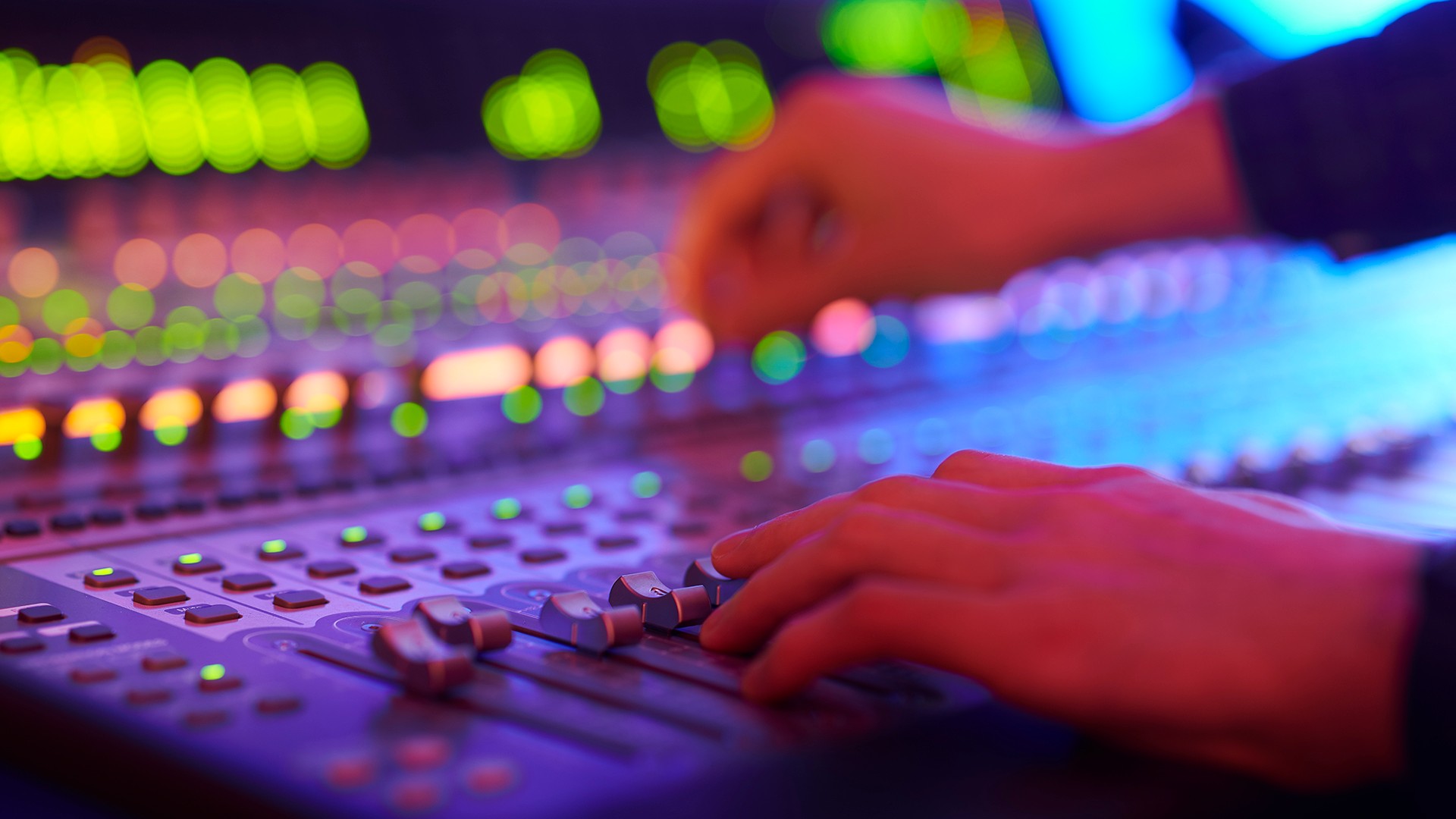 Hands operating a mixing desk.