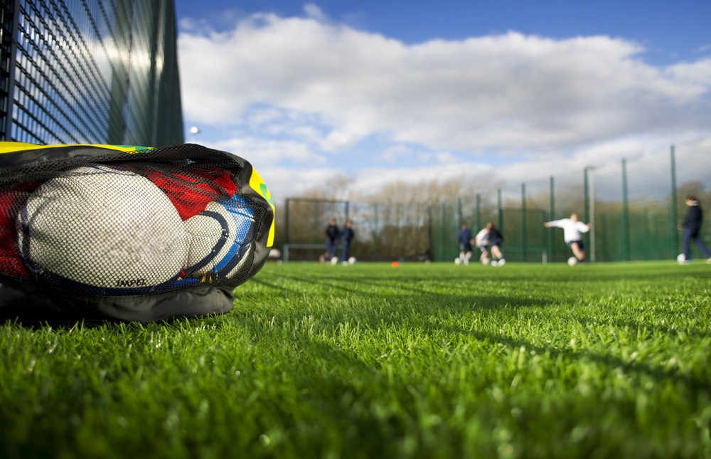 Sports Equipment on a grass pitch, with people playing sport in the background. 