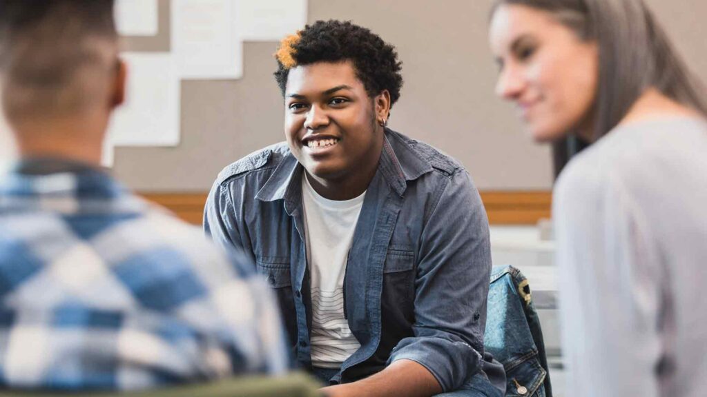 Three students sat in a circle, laughing.